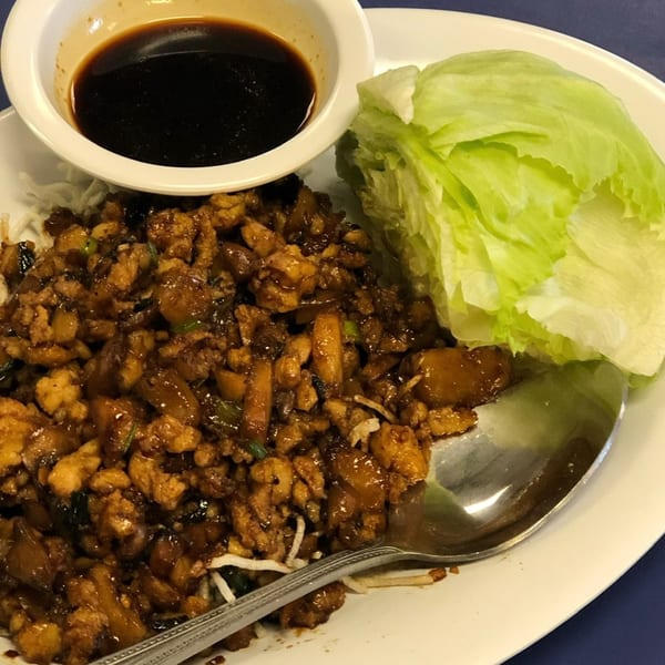 Mei Hon Chinese Restaurant's chicken lettuce wraps with a side of sauce and fresh lettuce.