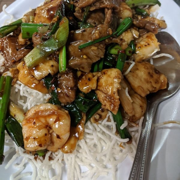 Mei Hon Chinese Restaurant's stir-fried chicken, beef, and shrimp with green onions over crispy noodles.